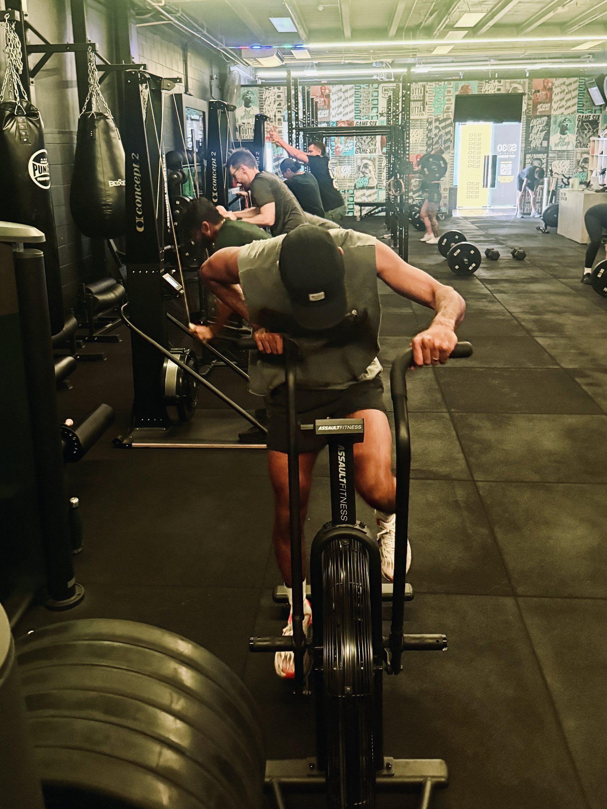 Members on the air bike and rowers during a conditioning class