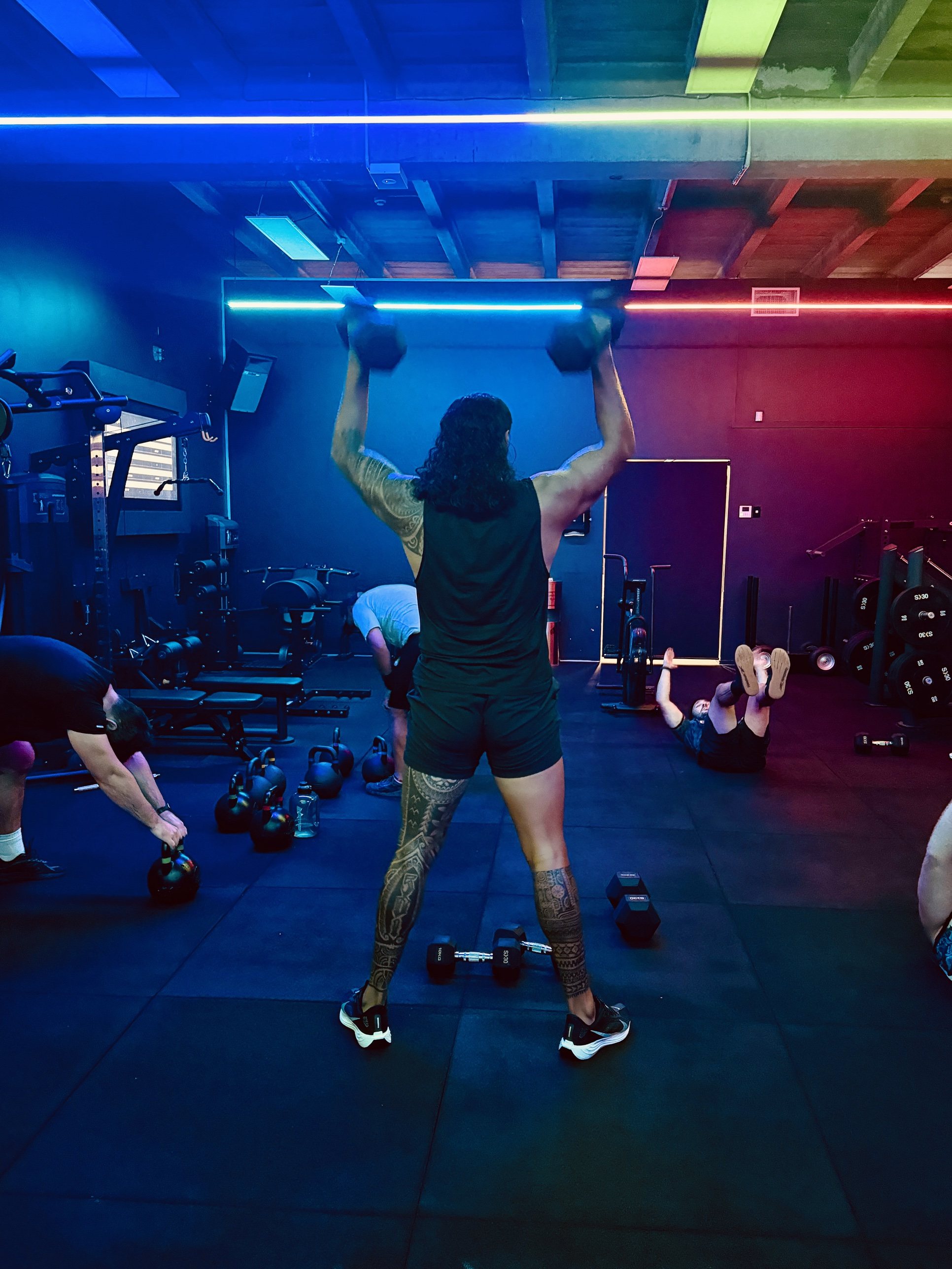 A member pressing dumbbells overhead in the studio